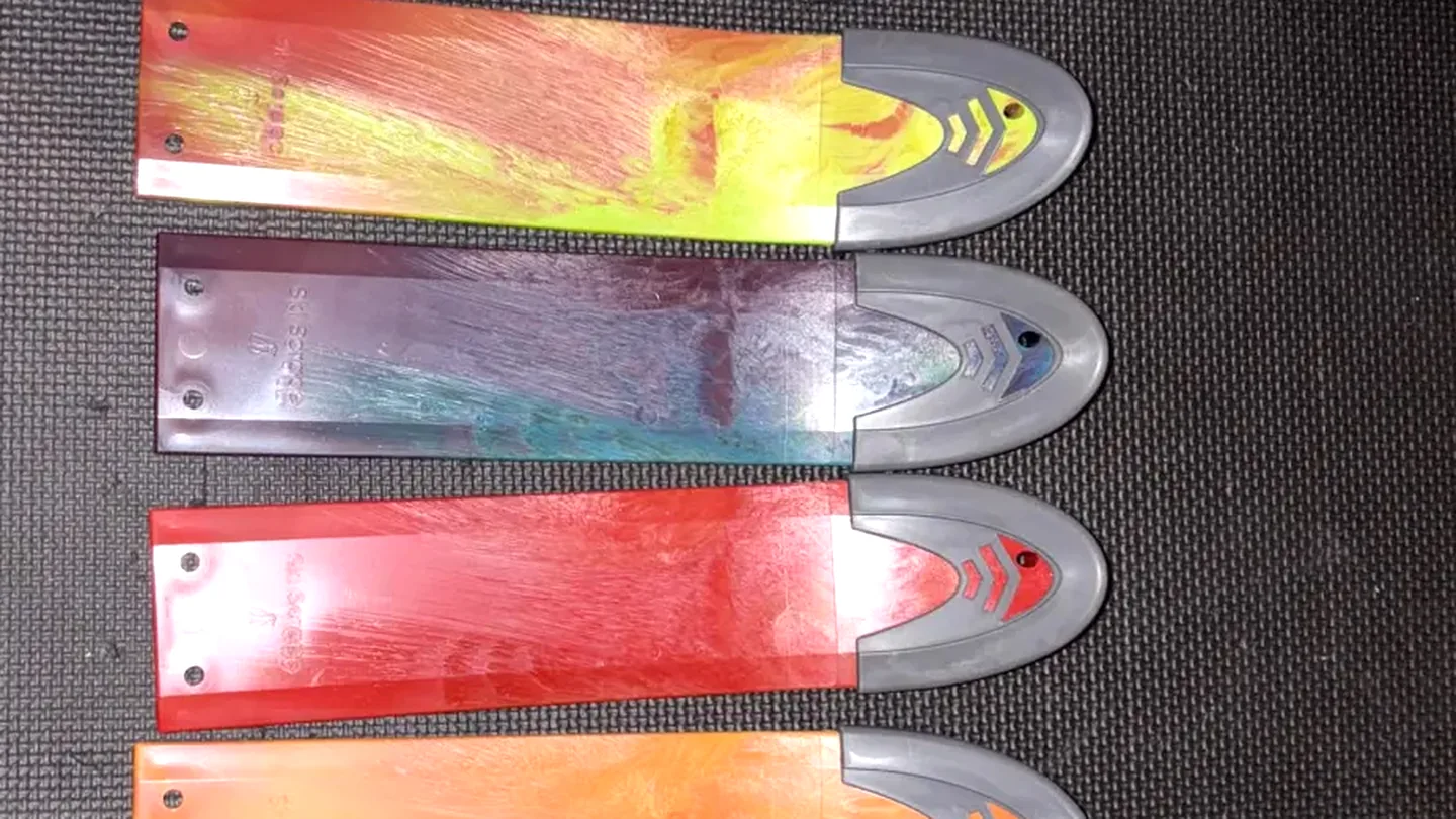 Three marbled scraper blades from one production run, laid out side by side, each folded differently.