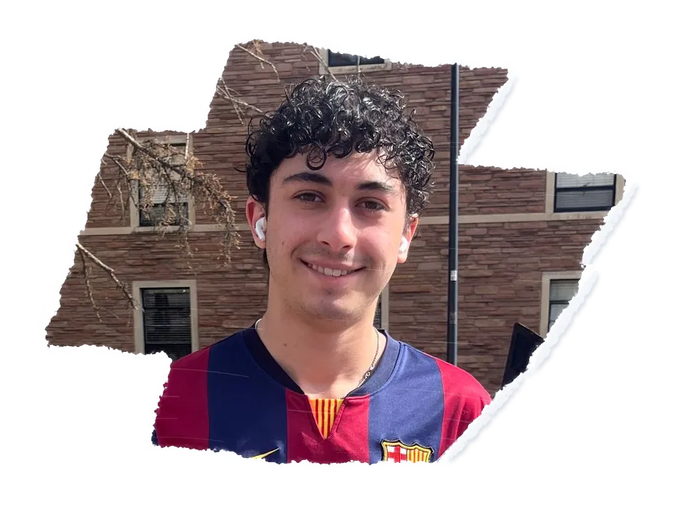 Someone in a football shirt smiling, a brick building in low winter sun behind them.