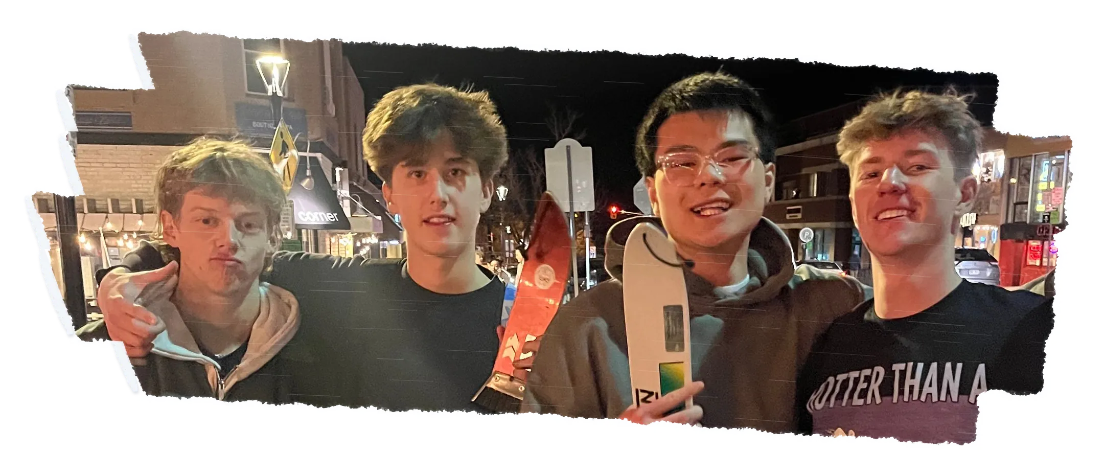 Four people side by side at night, two of them holding scrapers up.