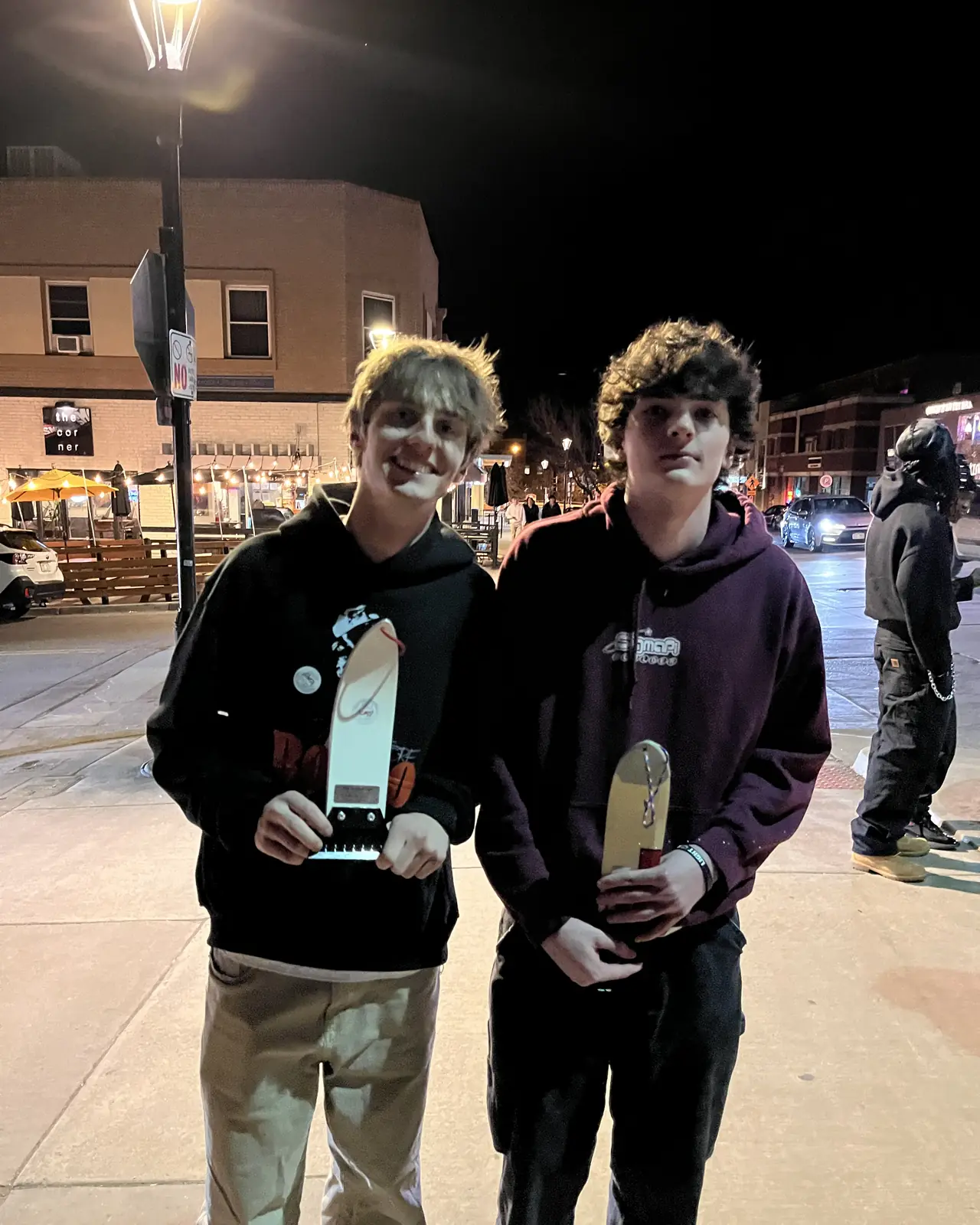 Two people standing shoulder to shoulder at night, a scraper each.